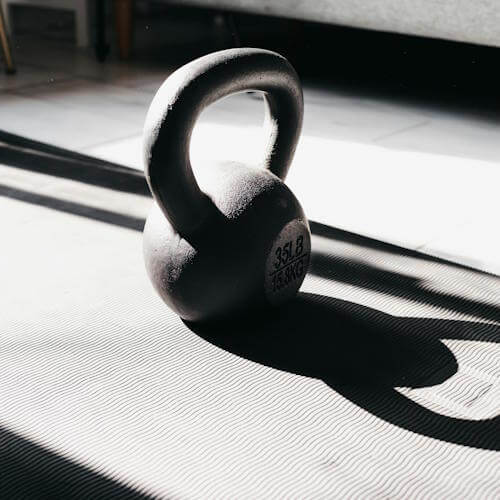 kettlebell die gebruikt wordt bij personal training staat met een mooie schaduw op de vloer